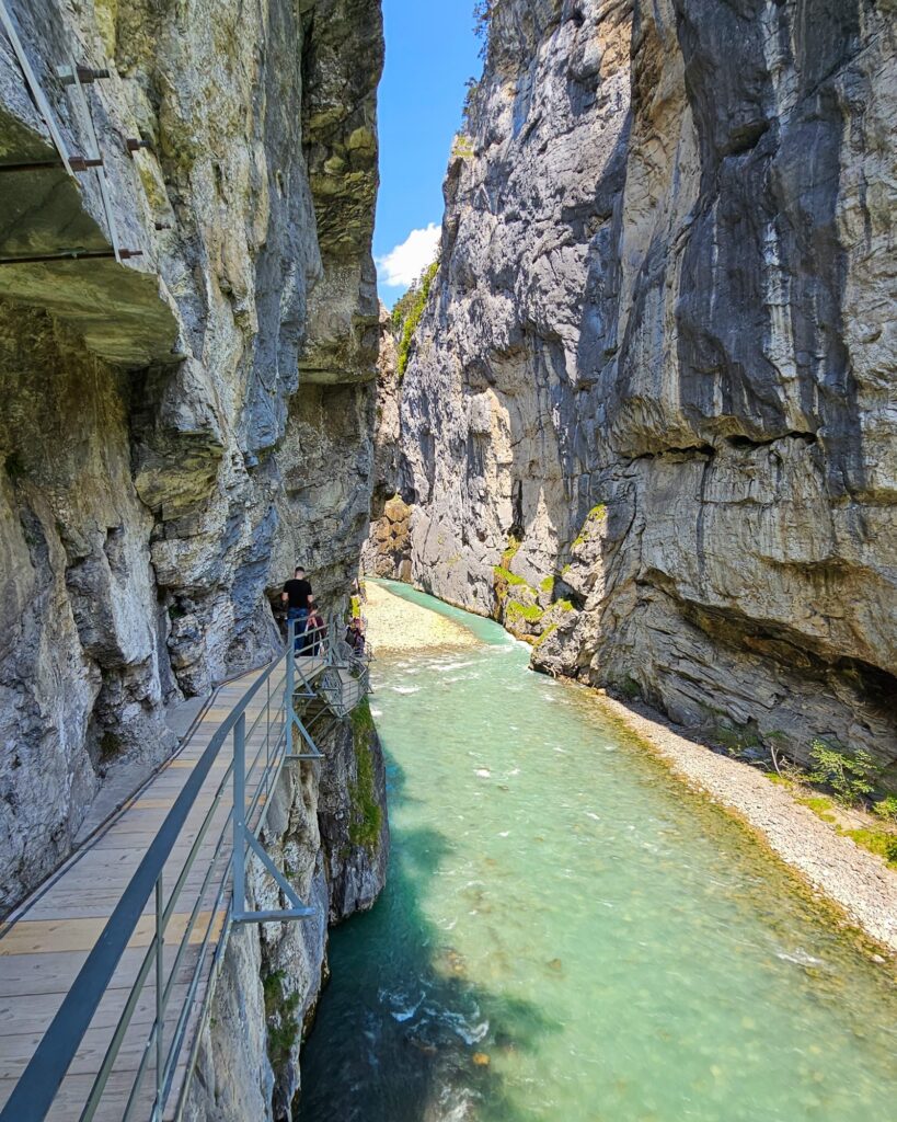 Open part of the Aare Gorge with a boardwalk on the cliff, gravel banks and a green river