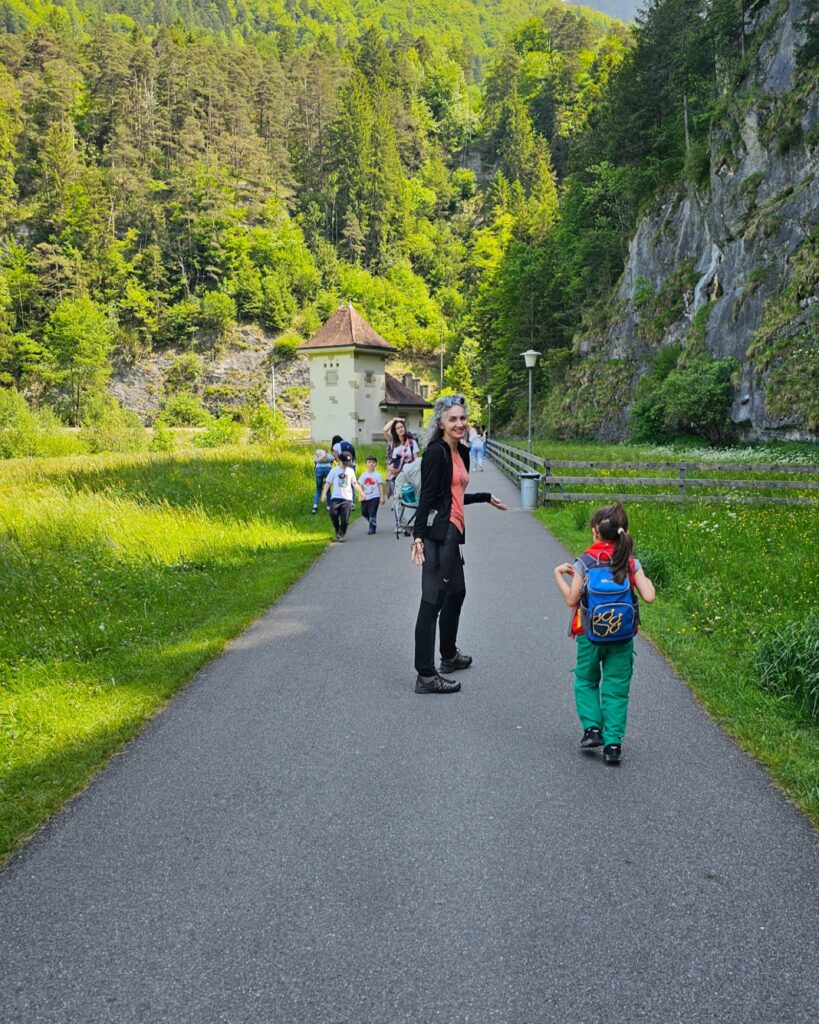 Paved path through meadows near the Aare Gorge, a woman looking back and a child walking