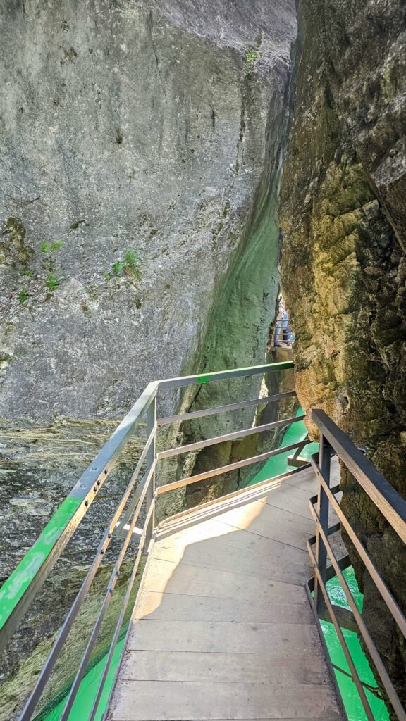 Wooden steps with green railings between narrow rock walls in the Aare Gorge