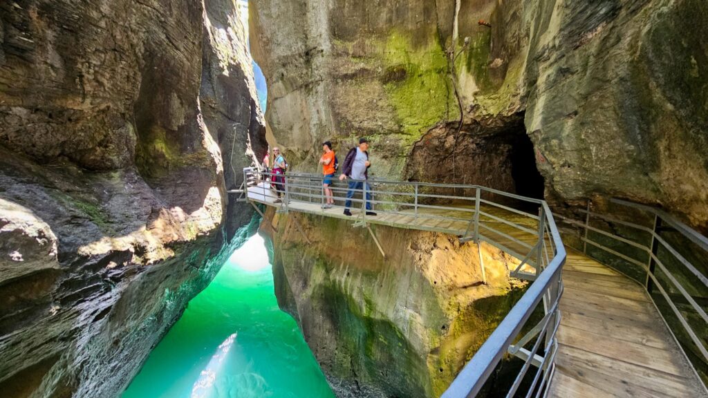 Visitors on a viewing walkway above bright green water in the Aare Gorge