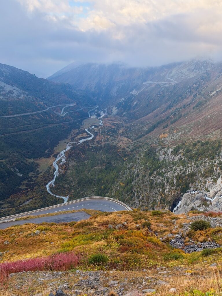 Furka Pass road and hairpin bends above the valley, slopes in autumn colours