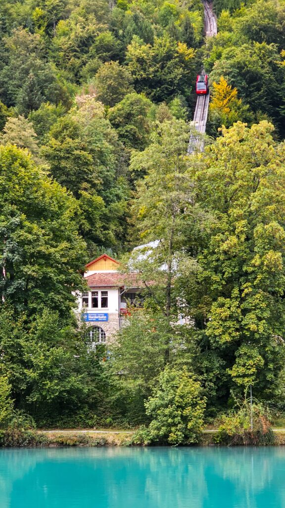 Red Harder Kulm funicular climbing through the forest above the turquoise Aare in Interlaken