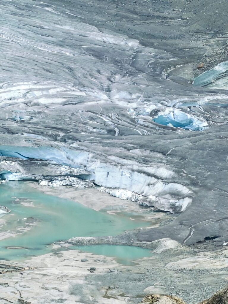 Blue ice at the front of the Rhône Glacier, with meltwater pools below